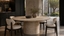 Round travertine pedestal dining table with ivory upholstered chairs, black oak joinery and courtyard light, showing timeless natural stone premium furniture.