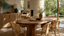 Rattan and cane dining chairs around a solid timber dining table in a sunlit Australian interior with woven storage, greenery and warm luxury furniture materials.