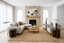 Calm, minimalist living room featuring a grey L-shaped sofa, matching armchairs, woven rug and round timber coffee table.