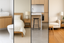 Four modern rooms side by side: a bathroom with white tile flooring, a carpeted bedroom, a kitchen with polished concrete, and a living room with timber floors in a neutral, minimalist style.