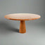 Elegant round dining table crafted from red travertine stone, featuring a smooth polished surface and a conical pedestal base.