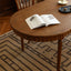 Oval wooden dining table with turned legs on geometric patterned rug