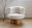 White boucle armchair with rounded cushions on wooden cylindrical base