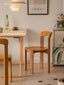Terracotta and black minimalist wooden dining chairs on light wood floor