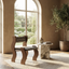 Walnut wood chair with patterned seat in a room with a large window and decorative plant.