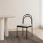 Black metal chair with arched backrest and cushioned seat.