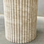 fluted travertine pedestal on a neutral background