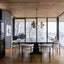 Modern dining room with marble table and white chairs, large windows, and wooden ceiling.