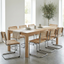 Dining room with a long wooden table and wicker chairs in a bright room.