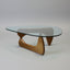 Glass triangular coffee table with wooden base on a gray background