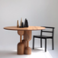 Round medium-toned wood dining table with sculptural base