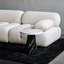 Conora side table with black marble base and white marble top placed in front of a white sofa on a black rug