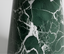 Close-up of green marble vase with white veins on a light gray background