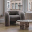 Gray curved armchair with cylindrical sides and plush upholstery