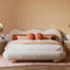 Plush wood, sponge, and fabric bed with curved headboard.