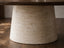 Close-up of the Serena dining table beige travertine pedestal base showing natural stone pores, veining and tapered form.