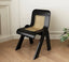 Black retro chair with angled legs and rattan backrest.
