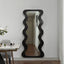 Full-length black mirror with dramatic wavy frame design