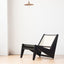 Minimalist black wood and rattan low-profile chair.
